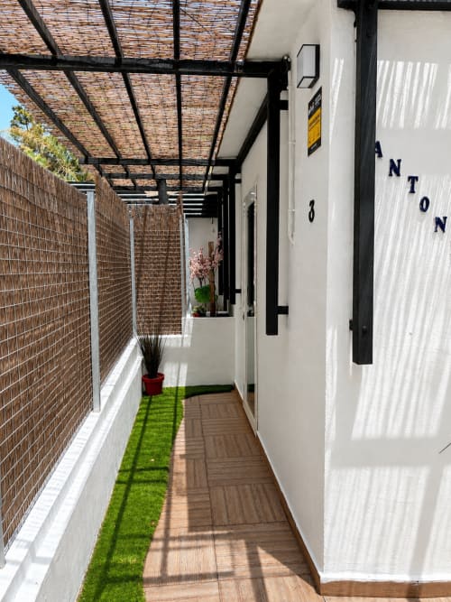 Private patio with woven pergola, brick walls, artificial grass, and wooden decking at Apartamentos Turísticos Axarent in