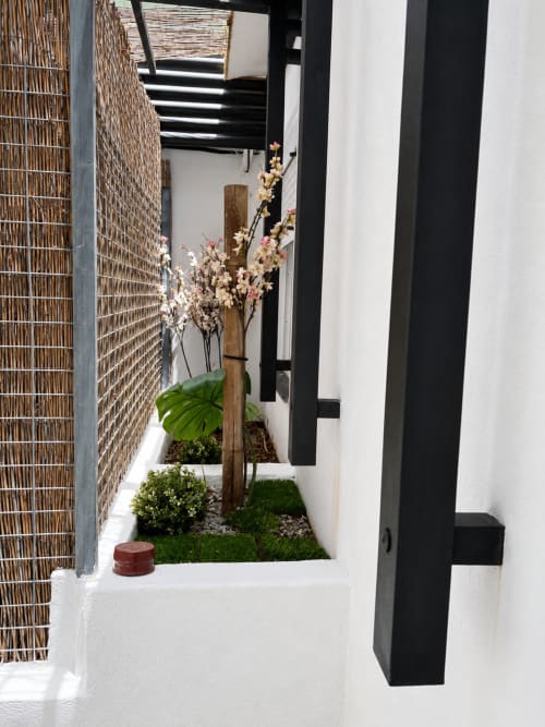 Modern patio entrance with decorative plants, wooden beam, and black frame door at Apartamentos Turísticos Axarent, Almayate