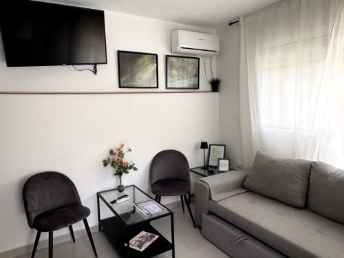 Modern living room in Almayate Alto apartment with gray sofa, black chairs, flat-screen TV, air conditioning, and sea view