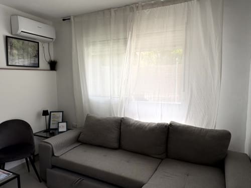 Bright living room with gray sofa, white curtains, AC unit, and sea views at Apartamentos Axarent, Almayate Alto