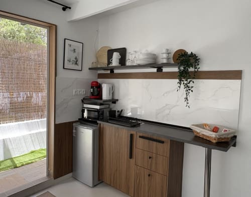 Modern kitchenette in Apartamentos Turísticos Axarent with wooden cabinets, marble backsplash, and shelving, opening to patio