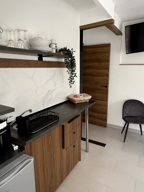 Modern kitchen in Almayate Alto apartment with wooden cabinets, black countertop, marble backsplash, and dining area