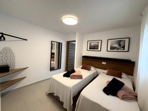 Twin beds with brown headboards in bright bedroom at Apartamentos Turísticos Axarent, Almayate Alto
