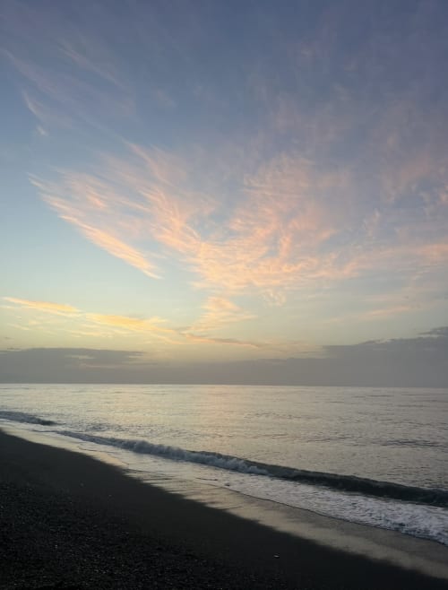 Sunset over the Mediterranean Sea at Almayate beach with golden clouds and gentle waves