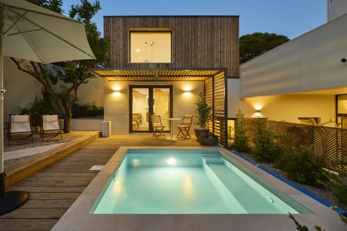 Vila moderna em Caparica com piscina iluminada, deck de madeira e arquitetura contemporânea ao entardecer