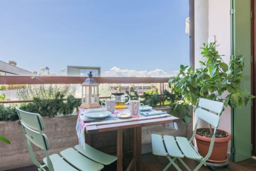 Dachterrasse des Casa Pleiadi Apartments in Sirmione mit Esstisch, grünen Stühlen, Topfpflanzen und Stadtblick