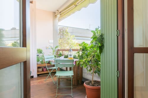 Sonniger Balkon in Casa Pleiadi, Sirmione, mit Mintgrünem Stuhl, Topfpflanzen und Gartenblick