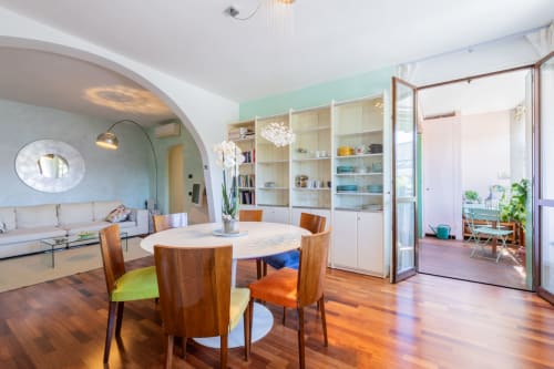 Moderner Essbereich im Apartment Casa Pleiadi bei Prince Garda, Sirmione, mit rundem Holztisch und farbigen Stühlen