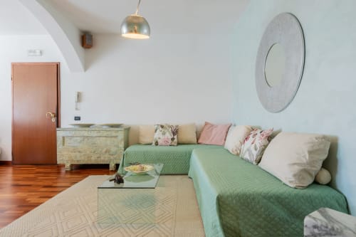 Modernes Wohnzimmer in Casa Pleiadi am Prince Garda, Sirmione, mit grünem Sofa, Dekospiegel und Gartenblick