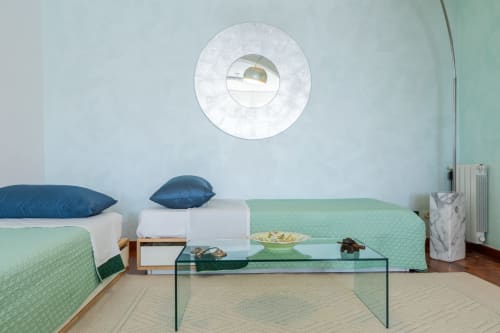 Modernes Schlafzimmer der Wohnung Prince Garda Sirmione mit Einzelbetten, grünen Steppdecken, blauen Kissen, Glastisch und rundem Design