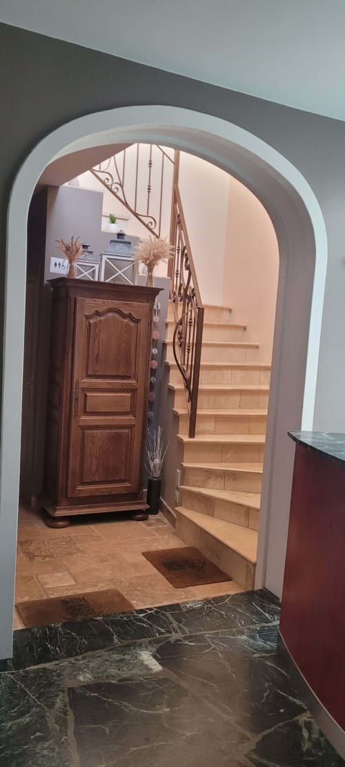 Elegant arched entryway at Villa Varco Auxonne, leading to staircase with decorative iron railing and wooden door
