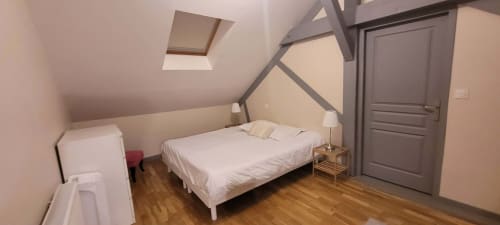 Modern attic bedroom at Villa Varco Auxonne with queen bed, exposed beams, skylight, and wooden floors