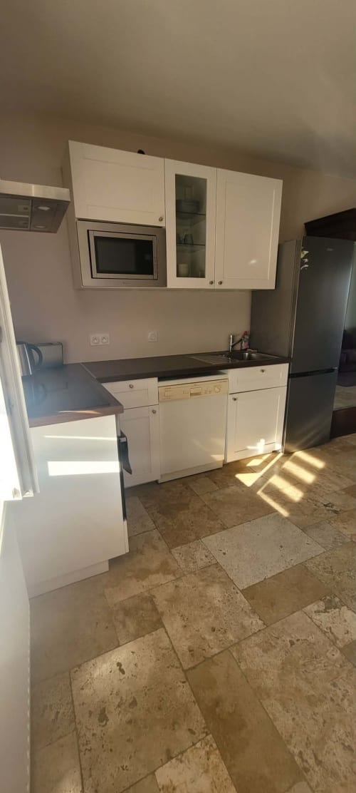 Modern kitchenette at Villa Varco suite in Auxonne with white cabinets, microwave, and black countertops