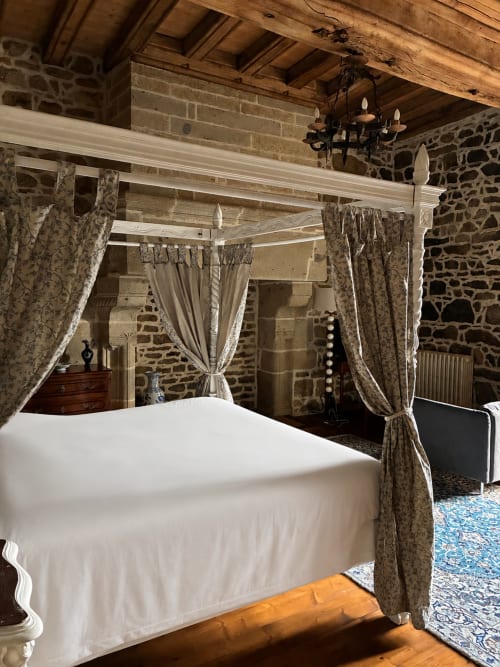 Lit à baldaquin luxueux aux rideaux fleuris dans une chambre de manoir médiéval au Manoir de Fornebello
