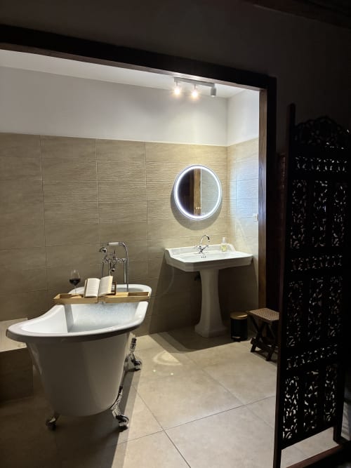 Salle de bain luxueuse de la Chambre Royale au Manoir de Fornebello avec baignoire îlot, lavabo sur colonne et miroir lumineux