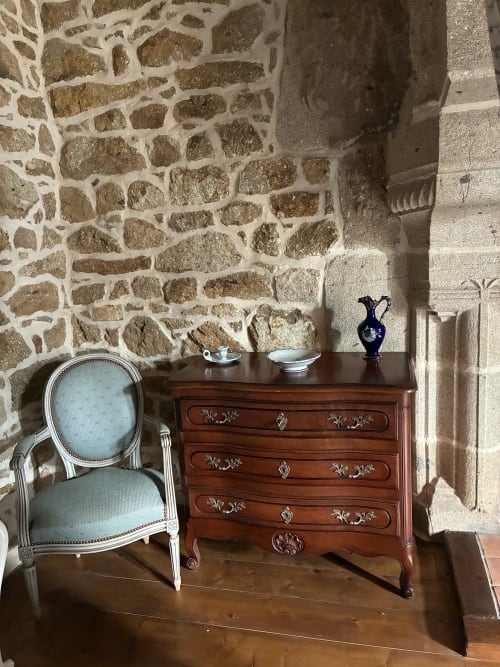 Élégant salon du Manoir de Fornebello avec fauteuil Louis XVI en tissu bleu et coffre en bois sculpté