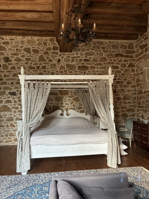 Lit à baldaquin élégant aux rideaux motifs et structure blanche dans la Chambre Royale du Manoir