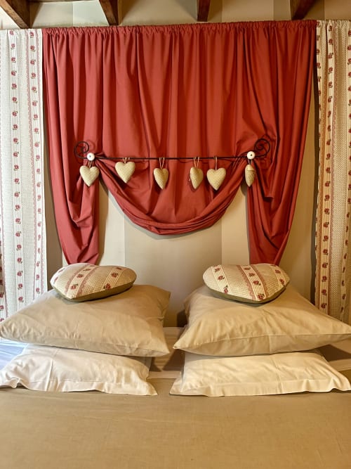 Lit à baldaquin romantique avec draperies rouges et guirlande de cœurs à Domaine De La Ferme De Ribeaufontaine, Dorengt