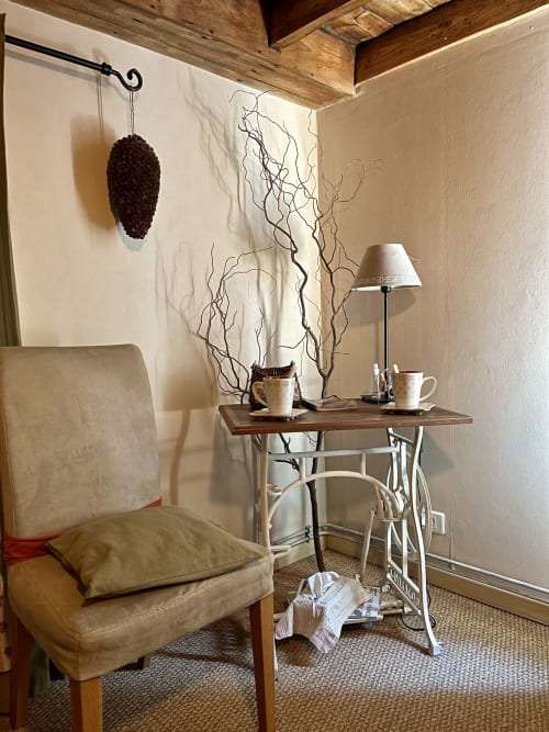 Un coin douillet dans la chambre La Bétise de Schum au Domaine De La Ferme De Ribeaufontaine avec fauteuil beige, table en bois, lampe et