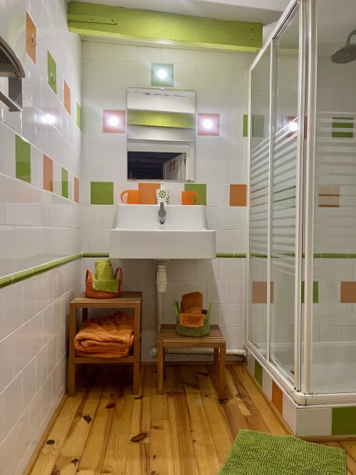 Salle de bains moderne avec carrelage coloré, lavabo blanc, miroir et douche à Domaine De La Ferme De Ribeaufontaine