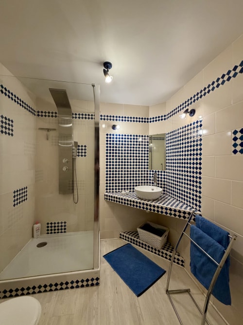 Salle de bain contemporaine avec carrelage losanges noir et blanc, douche à l'italienne, vasque design et serviettes bleues au Domaine De La