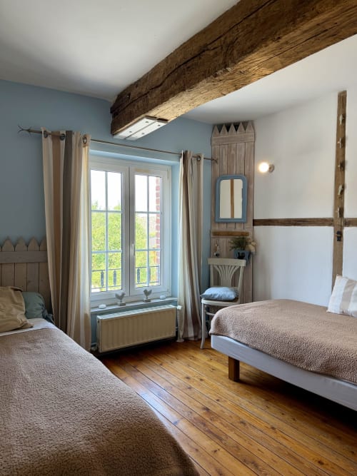 Suite familiale rustique avec lits jumeaux, poutre bois apparente, murs bleu pastel et vue sur le jardin