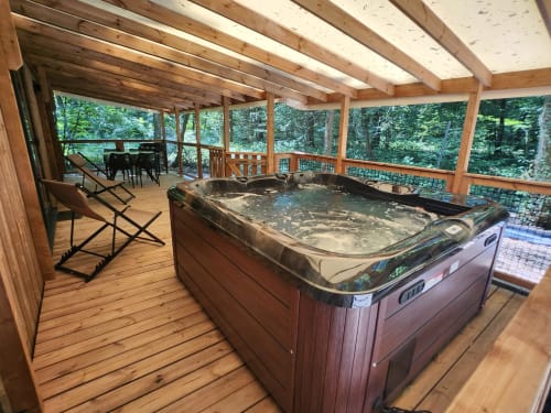 Terrasse couverte en bois avec bain à remous à la villa Les Chalets Du Lac à Marange-Silvange, vue sur la forêt