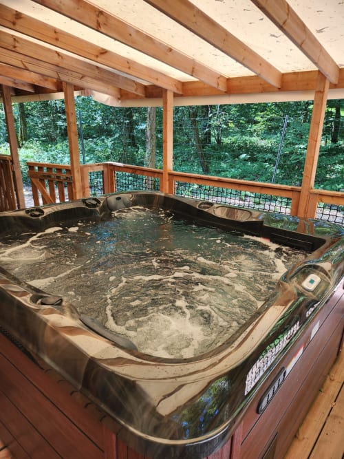Bain à remous extérieur sur terrasse en bois avec vue sur la forêt à la villa Les Chalets Du Lac