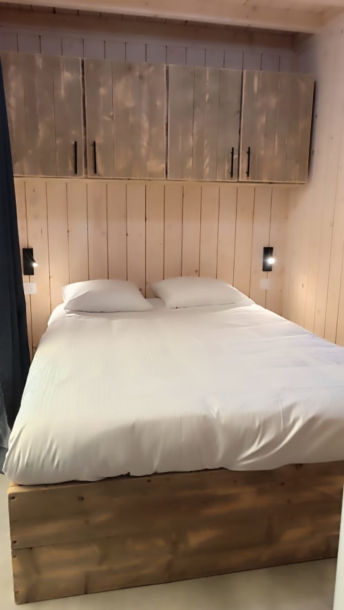 Chambre moderne de la villa Les Chalets Du Lac avec literie blanche, tête de lit en bois avec vitrines et tables de nuit intégrées
