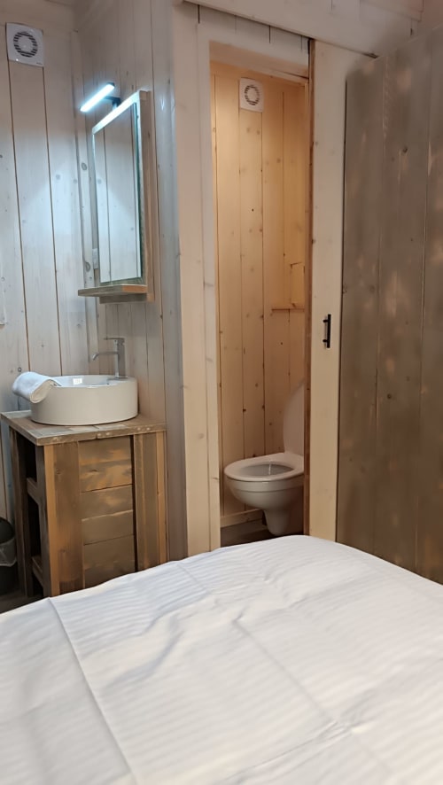 Salle de bain de la villa Verlaine avec vasque, miroir éclairé, toilettes et finitions en bois aux Chalets Du Lac