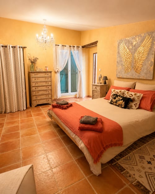 Chambre Lavande au Domaine Bellavigne avec murs dorés, sols en terre cuite et vue sur le jardin