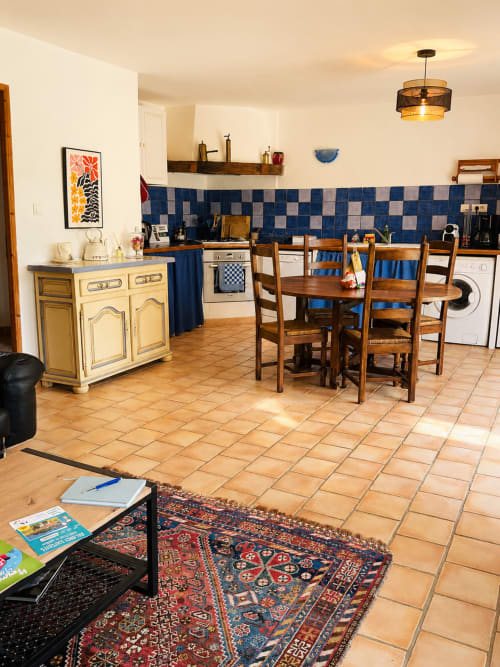 Spacieux séjour cuisine du gîte Romarin de Domaine Bellavigne avec carrelage bleu, table en bois et terre cuite