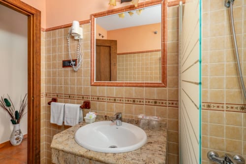 Modern bathroom with round white sink, granite countertop, and terracotta tile walls at Hotel Balcón De Los Montés in