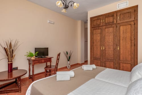 Chambre double spacieuse à l'Hôtel Balcón De Los Montés avec armoire en bois, bureau, télévision et vue sur la ville à Colmenar