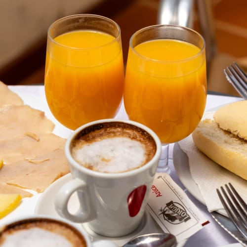 Petit-déjeuner à l'Hôtel Balcón De Los Montés avec jus d'orange, café et petits pains frais à Colmenar.