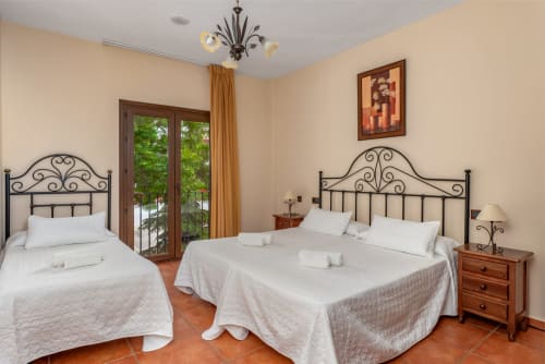 Chambre triple avec balcon à l'Hôtel Balcón De Los Montés de Colmenar, deux lits, têtes de lit en fer forgé, sol en terre cuite