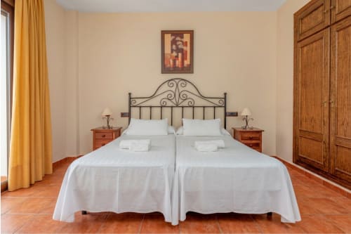 Deux lits jumeaux aux draps blancs dans la chambre triple de l'Hôtel Balcón De Los Montés, Colmenar