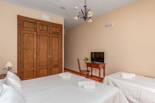 Chambre triple avec vue sur la ville à l'Hôtel Balcón De Los Montés à Colmenar, dotée de deux lits, d'une armoire en bois et d'une télévision