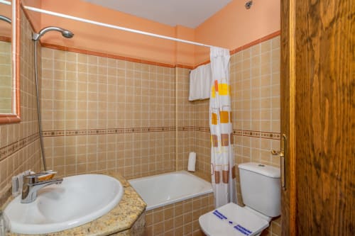 Salle de bains de l'Hotel Balcón De Los Montés à Colmenar avec carrelage beige, lavabo, toilettes et baignoire-douche