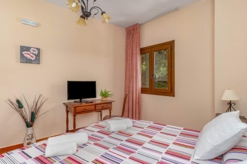 Chambre accessible à l'Hôtel Balcón De Los Montés à Colmenar avec literie colorée, TV, bureau en bois et fenêtres