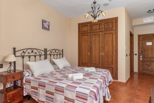 Chambre accessible aux fauteuils roulants à l'Hôtel Balcón De Los Montés à Colmenar avec armoire en bois et literie rayée