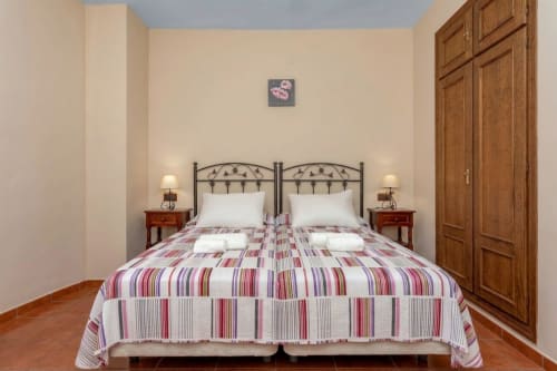 Chambre accessible de l'Hôtel Balcón De Los Montés à Colmenar avec literie rayée, mobilier en bois et vue sur la ville