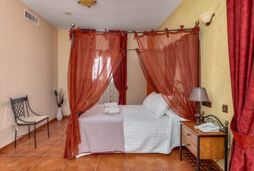 Suite élégante avec lit à baldaquin rouge et vue sur la ville à l'Hotel Balcón De Los Montés, Colmenar