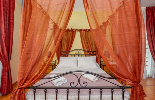 Lit à baldaquin luxueux aux rideaux orange à l'Hôtel Balcón De Los Montés à Colmenar, Espagne