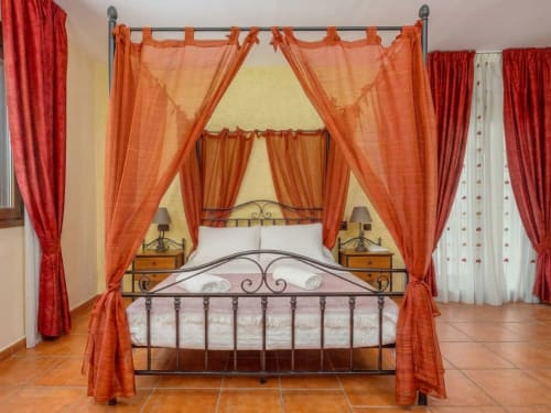 Lit à baldaquin de luxe aux draperies orange de la suite Hotel Balcón De Los Montés à Colmenar, Espagne