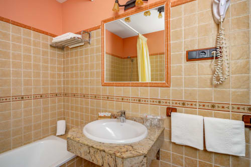 Salle de bains moderne avec lavabo rond, carrelage beige et miroir encadré orange à l'Hôtel Balcón De Los Montés à Colmenar