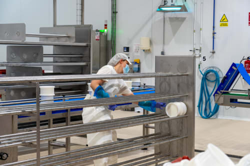 Employé en tenue blanche manipulant des articles dans les installations en acier inoxydable de l'Hôtel Balcón De Los Montés