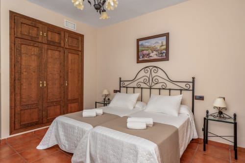 Spacieuse chambre double à l'Hôtel Balcón De Los Montés avec lit en fer forgé, armoire en bois et carrelage en terre cuite