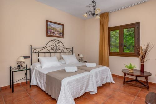 Spacieuse chambre double avec lit en fer forgé, sols en terre cuite et vue sur le jardin à l'Hôtel Balcón De Los Montés à Colmenar