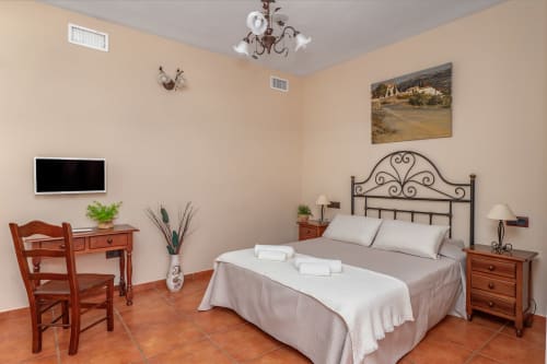 Suite spacieuse avec lit ornemental, bureau en bois, téléviseur, carrelage terre cuite et vue montagne à l'Hotel Balcón De Los